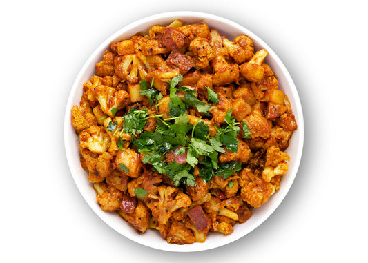 aloo gobi dish in white bowl under spice box